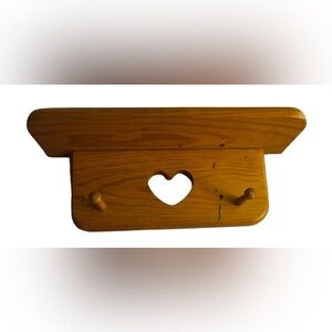 vintage-style wooden wall shelf with a heart cutout and pegs